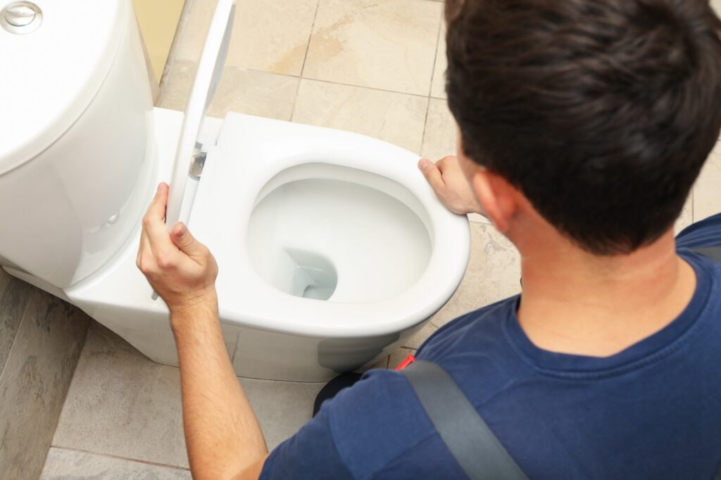 A Plumber in Overalls Fixes a Toilet