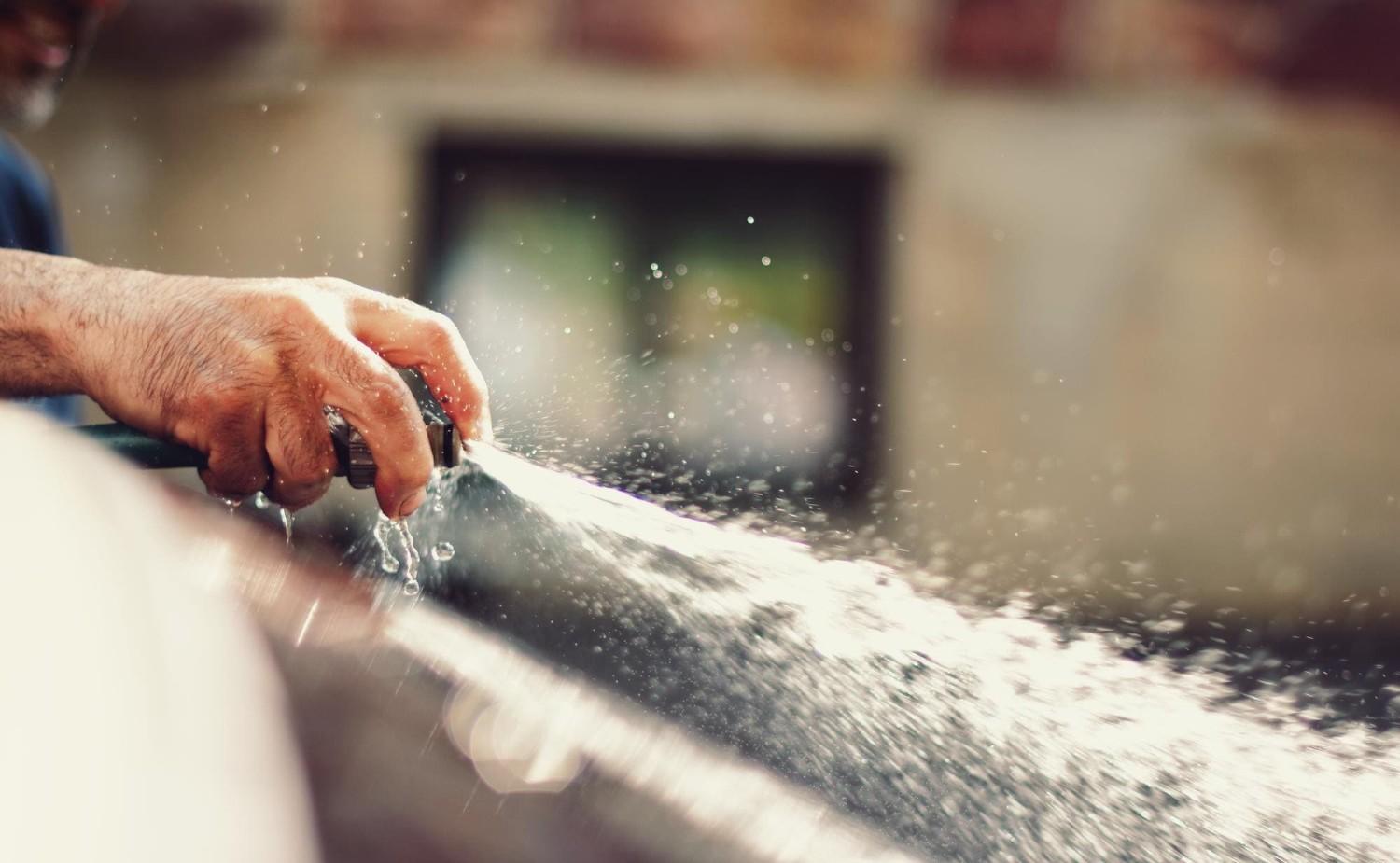 Water spraying from a hose, representing water-related services by Drain Pros Ventura, a plumber in Ventura.